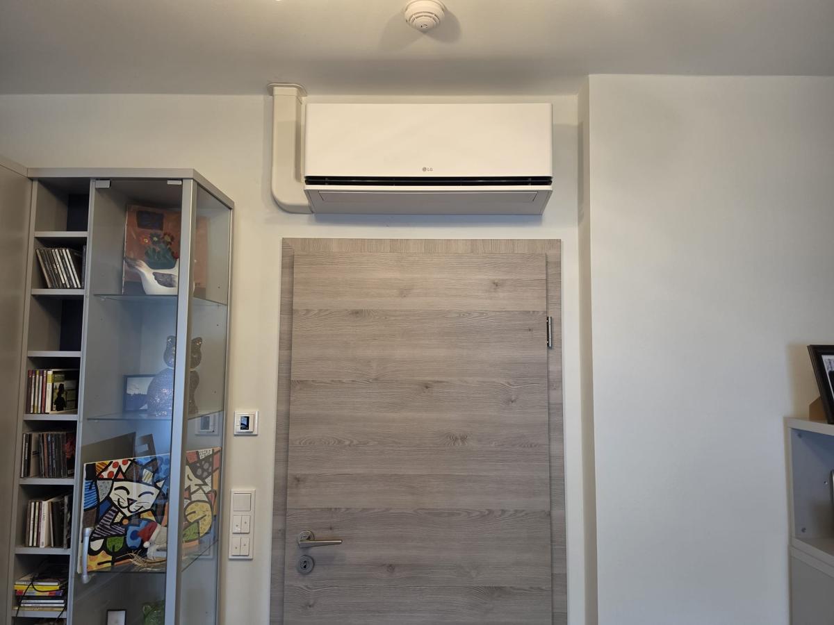 Split mural LG installé au-dessus d'une porte avec goulotte discrète au Luxembourg
